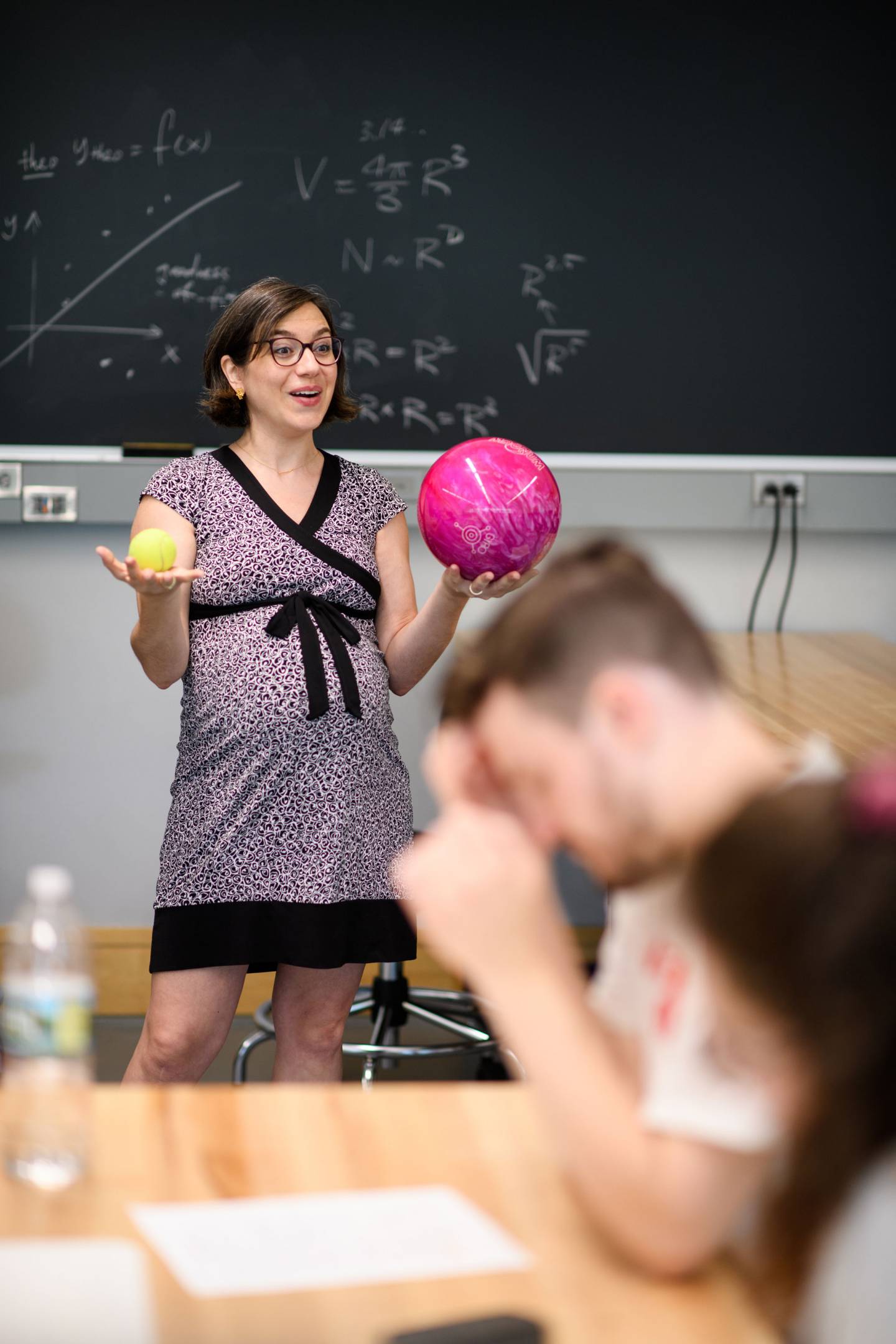 Katerina Visnjic standing in front of class holding a tennis ball and a bowling ball