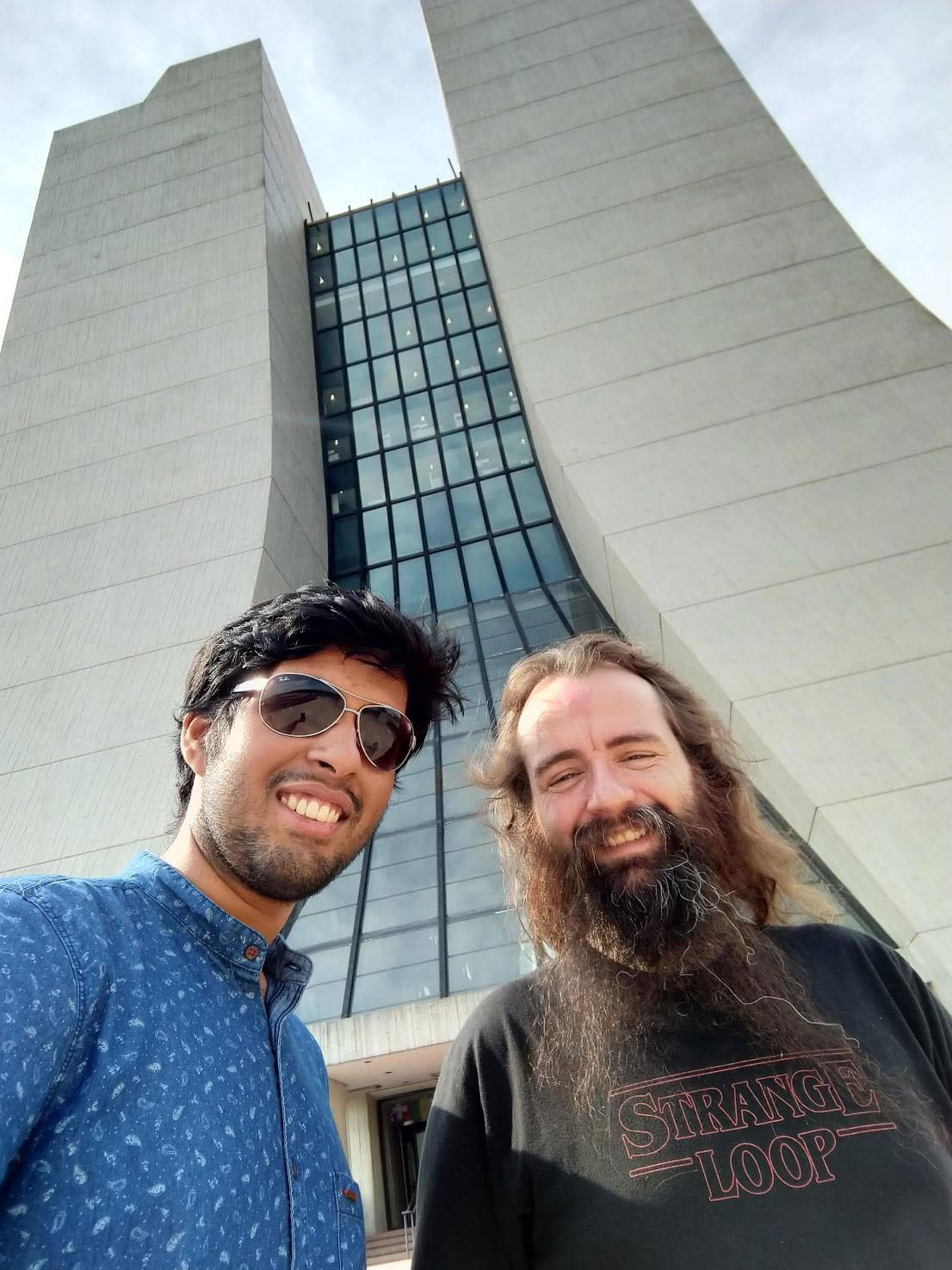 2 researchers pose in front a building