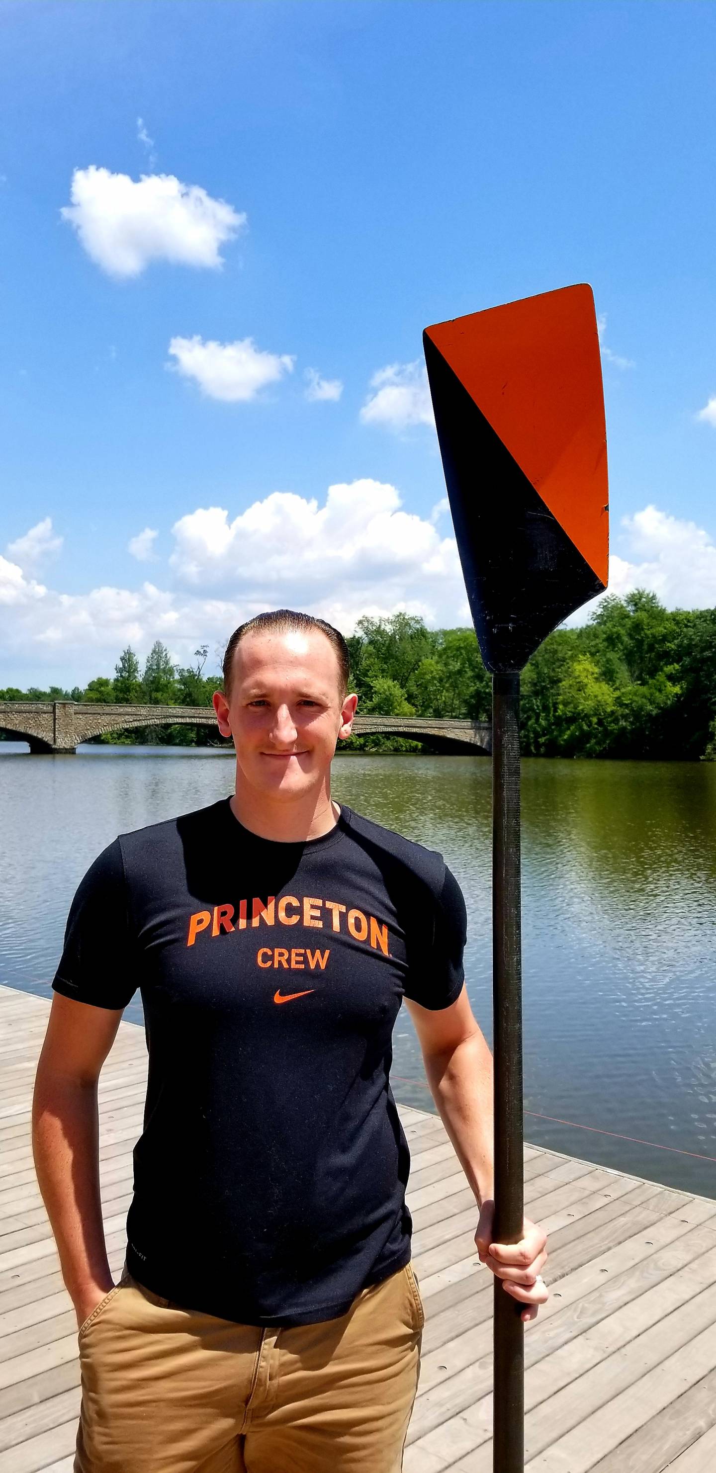 Student holding black and orange rowing oar