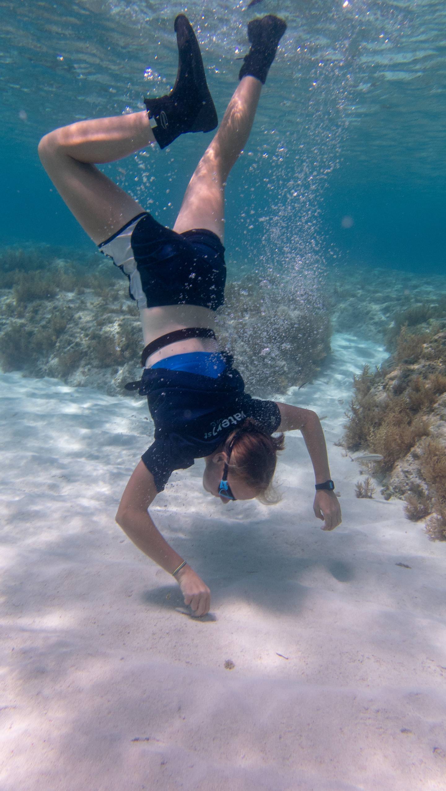 A student dives in tropical waters to get scientific samples of sand