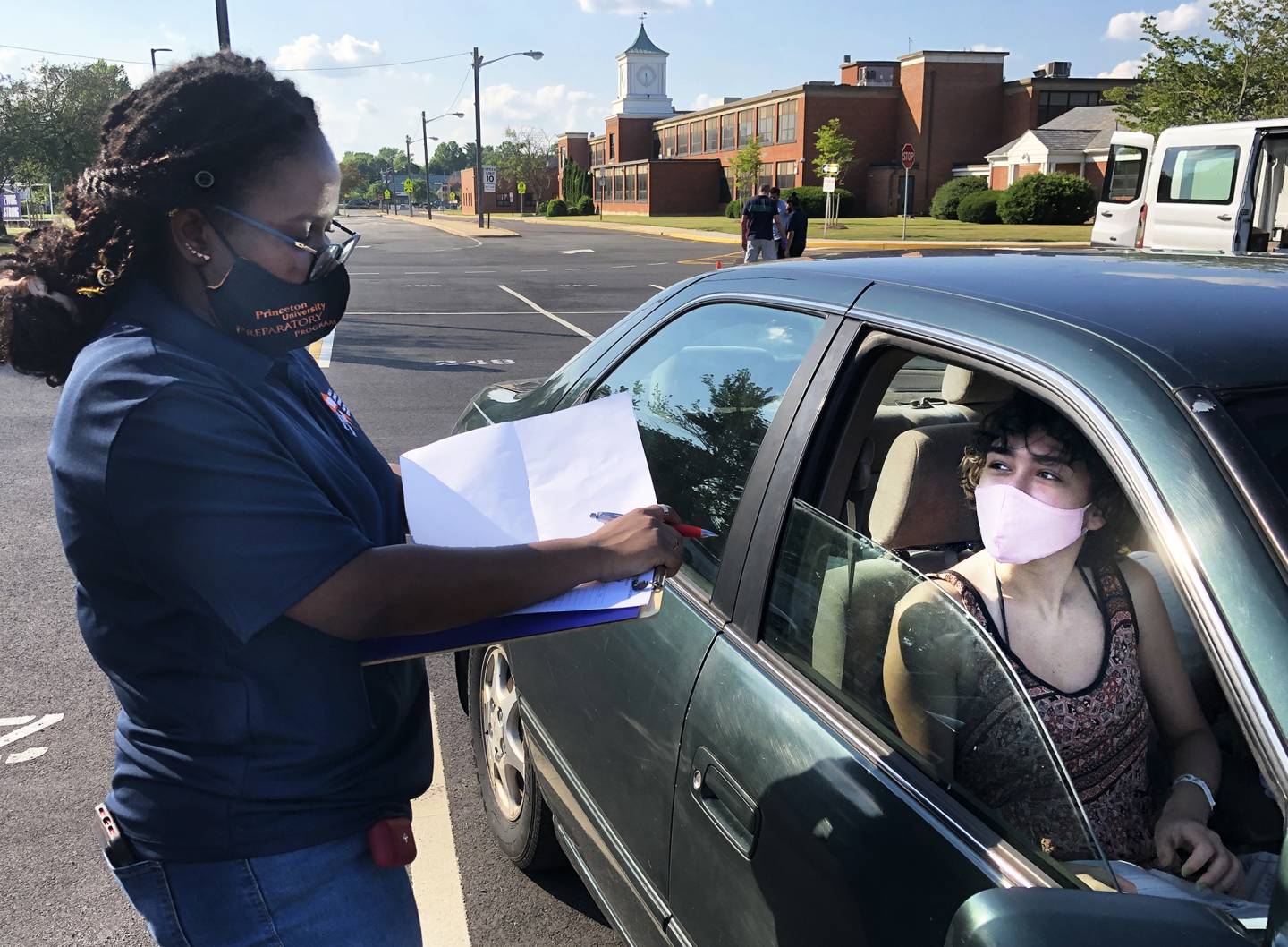 Teaching assistant at drive-up station doing PUPP program check-in