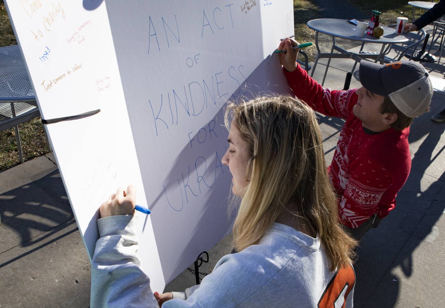 Two students sign up for an "act of kindess" on a large white board.