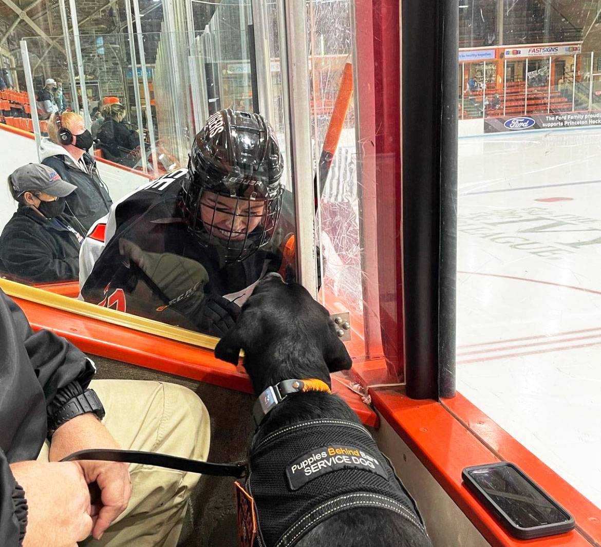 A member of the women's hockey team greets Coach through the glass