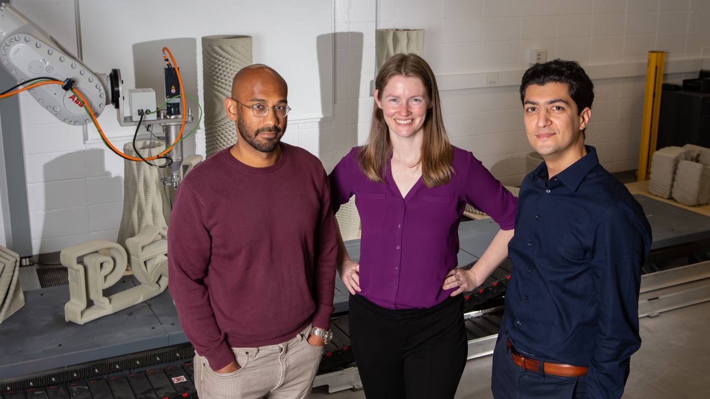 Three researchers in a lab with a robot arm