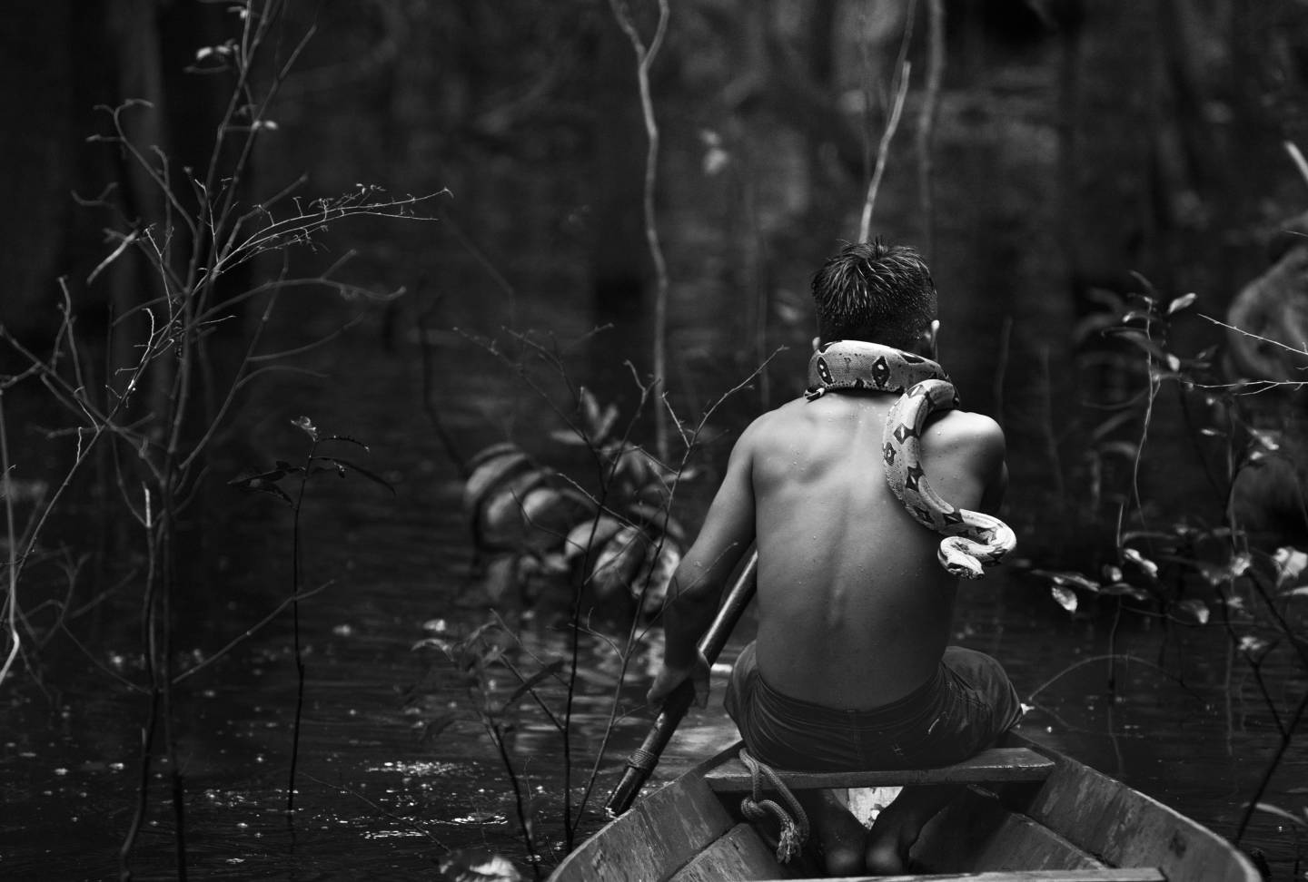 Boy with snake on should in a canoe