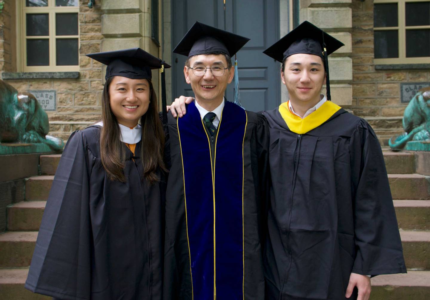 a professor poses with his two graduating children, all in graduation robes