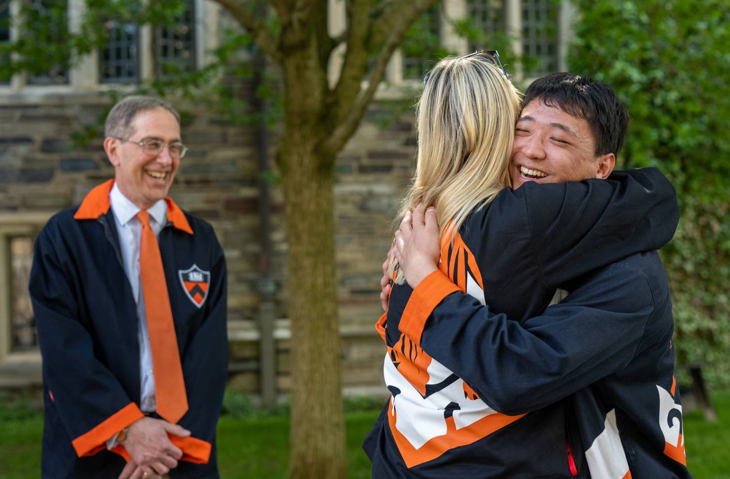 President Eisgruber watches two alumni embrace.
