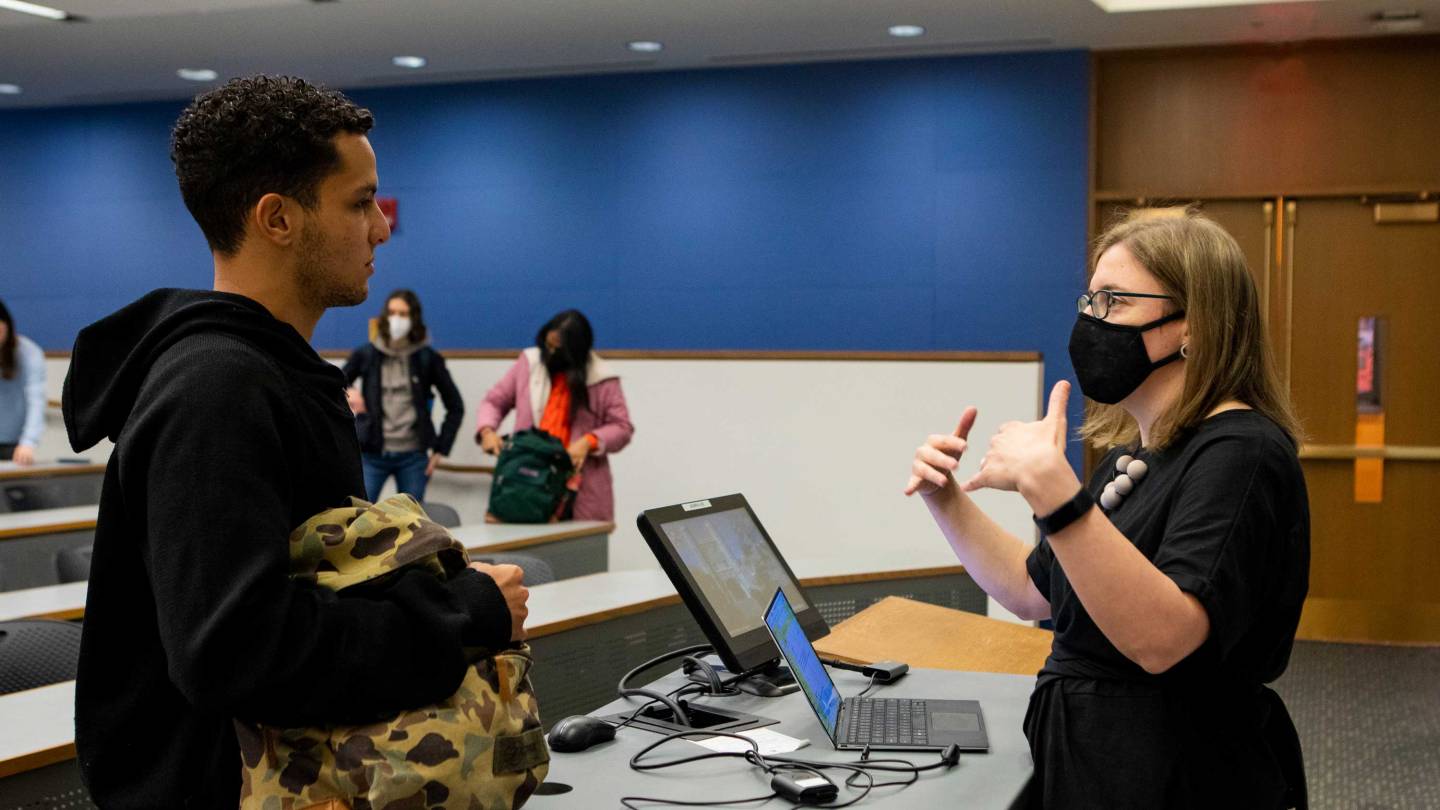 Kristina Olson talking to a student after lecture. Both are masked.