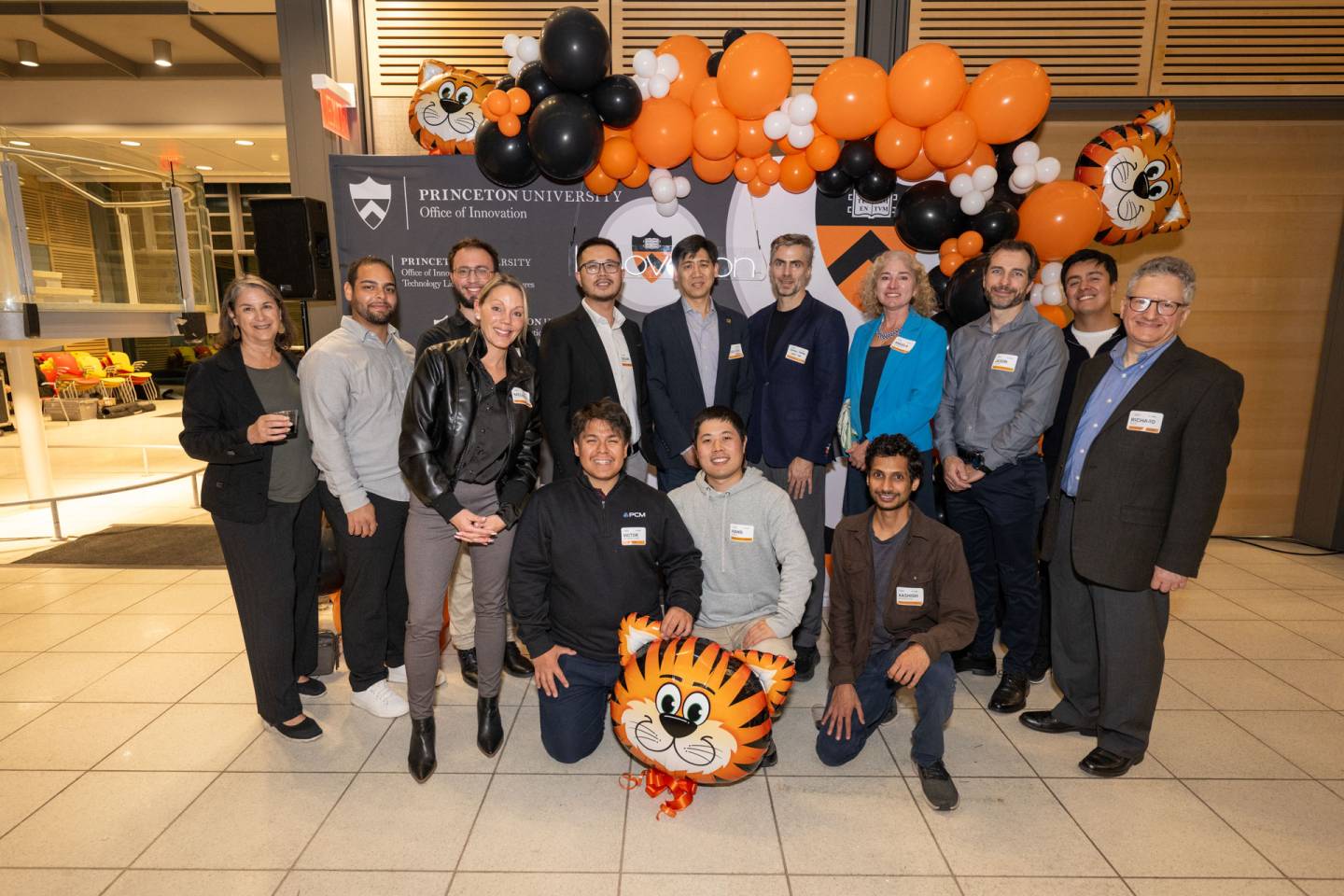 A group of researchers pose together smiling with orange and tiger balloons around them