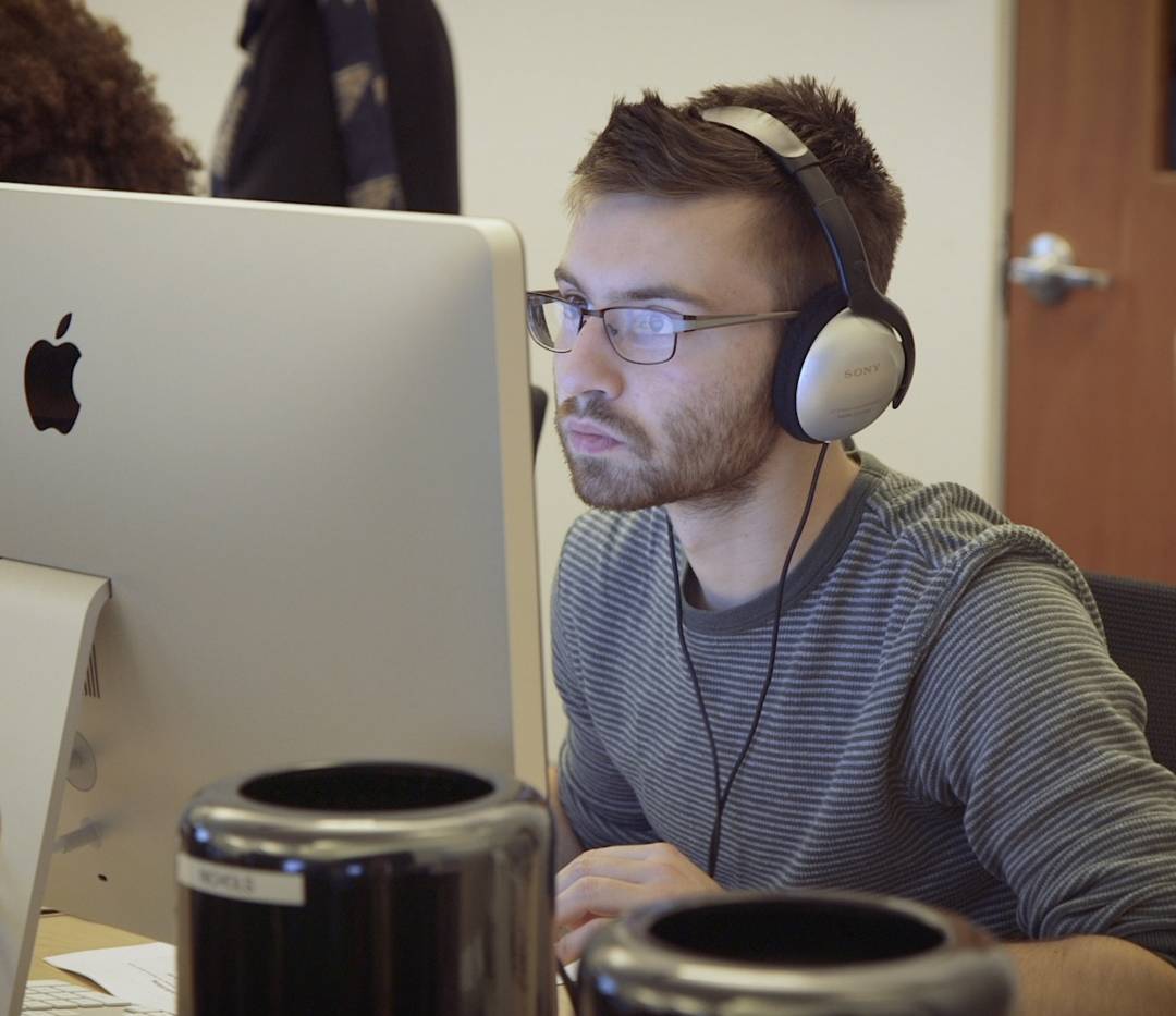 Student sits at computer screen wearing headphones