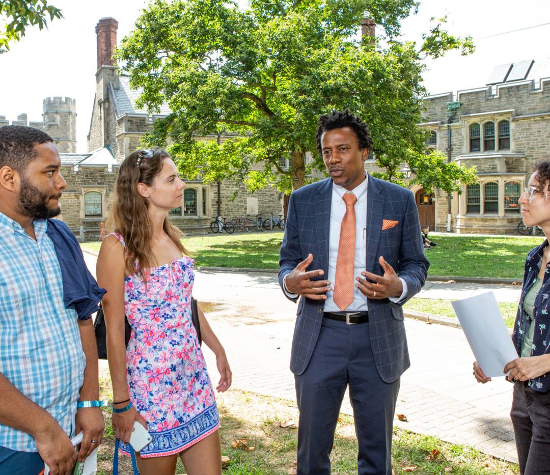 Dean of the Graduate School Rodney Priestley speaks with grad students outdoors on campus.