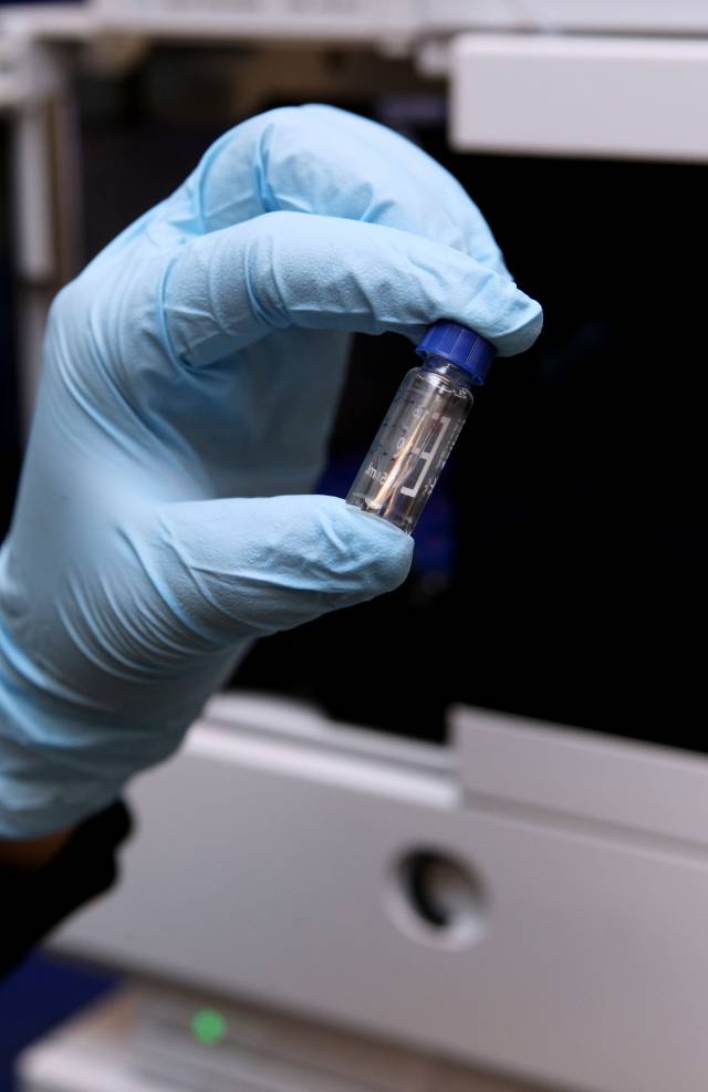 Gloved hand holding vial