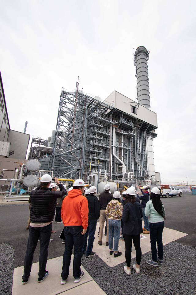 students in hard hats look at part of a power plant