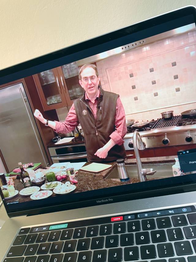 Christoper Eisgruber shown in a video, holding up an egg in a kitchen