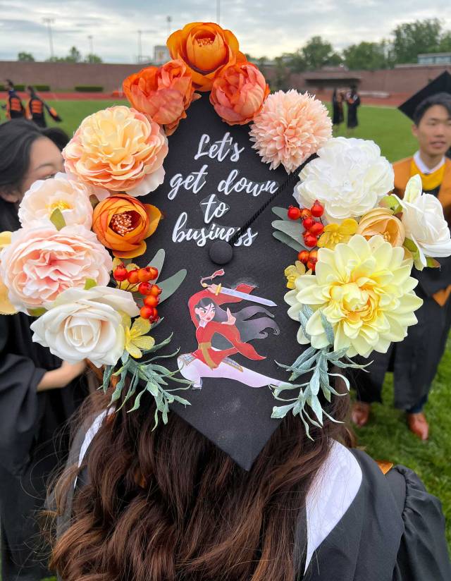 A decorated motarboard with flowers and "Let's get down to business" written on it