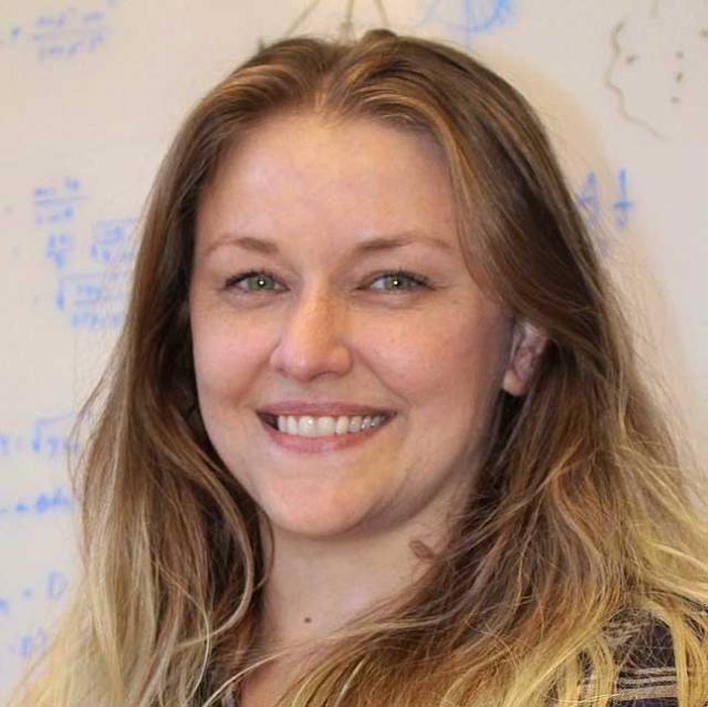 Ashley Chontos is smiling in front of an equation-filled whiteboard.