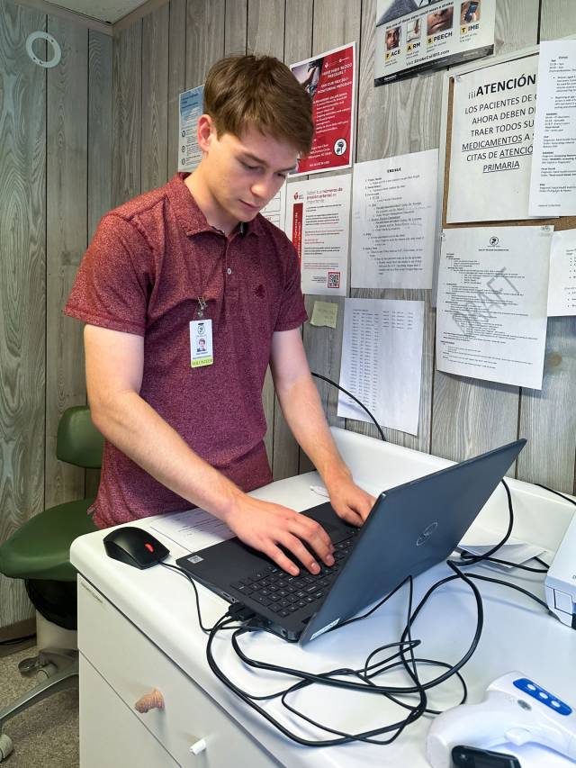 Sean Hession typing on laptop in health clinic room 