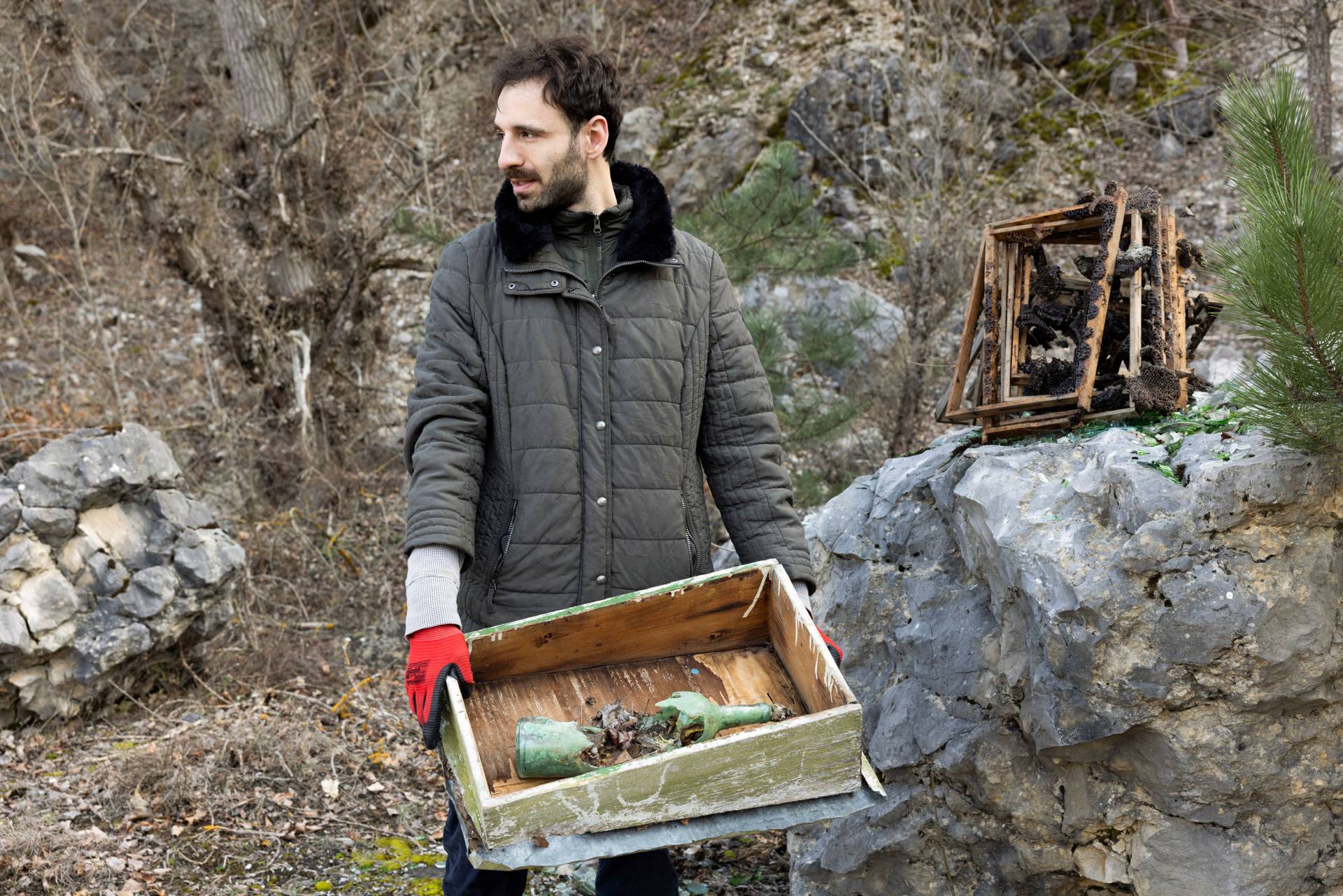 Julian Chehirian carries a broken bottle in a wooden crate 